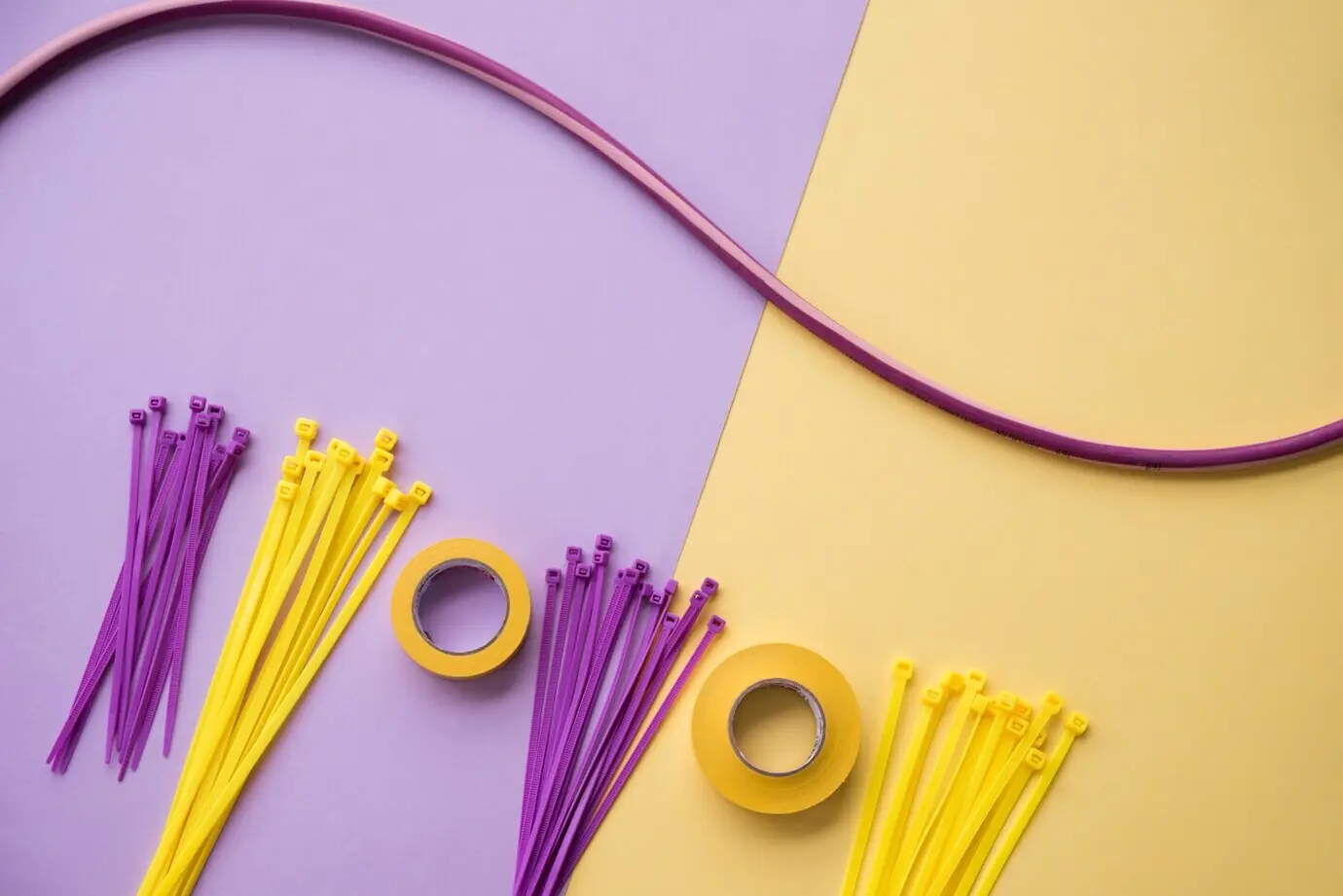 Insulating tape and nylon zip wire arranged on a dual purple-and-yellow backdrop.