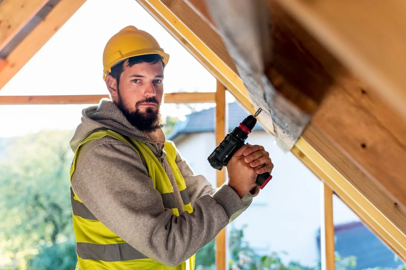 A man holds a hammer drill while looking away.